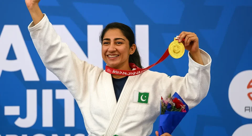 Banu Kausar celebrating gold medal win at Asian Jiu-Jitsu Championship 2024 wearing Pakistani uniform and holding medal on podium