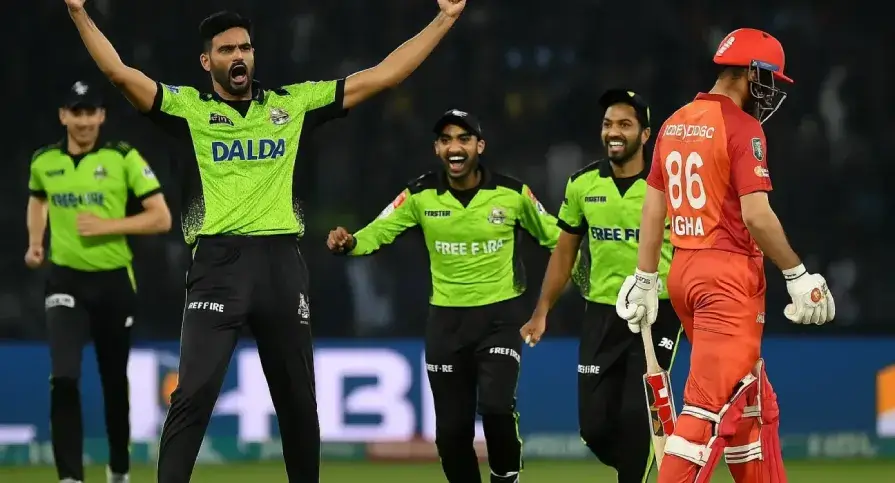 A high-action cricket moment showing Lahore Qalandars players celebrating a wicket during a PSL match, with fans cheering in the stadium under bright floodlights.